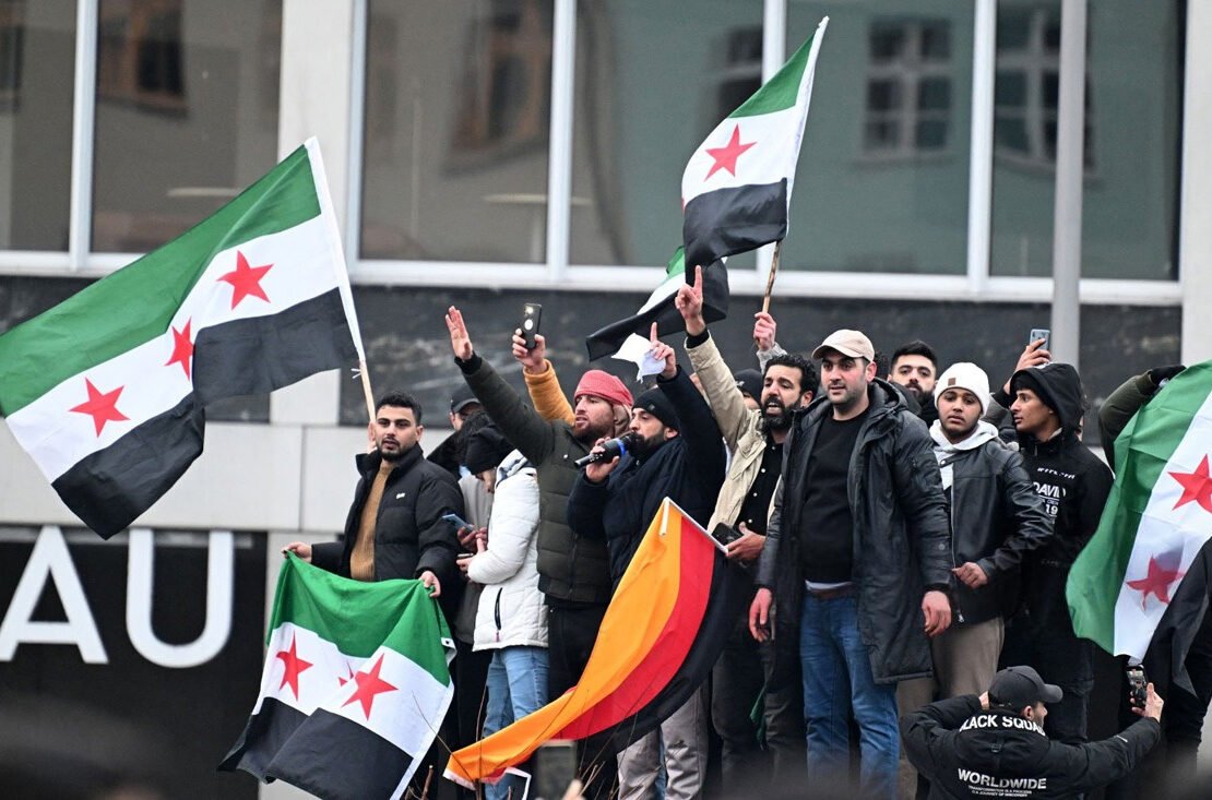 Menschen schwenken syrische Flaggen