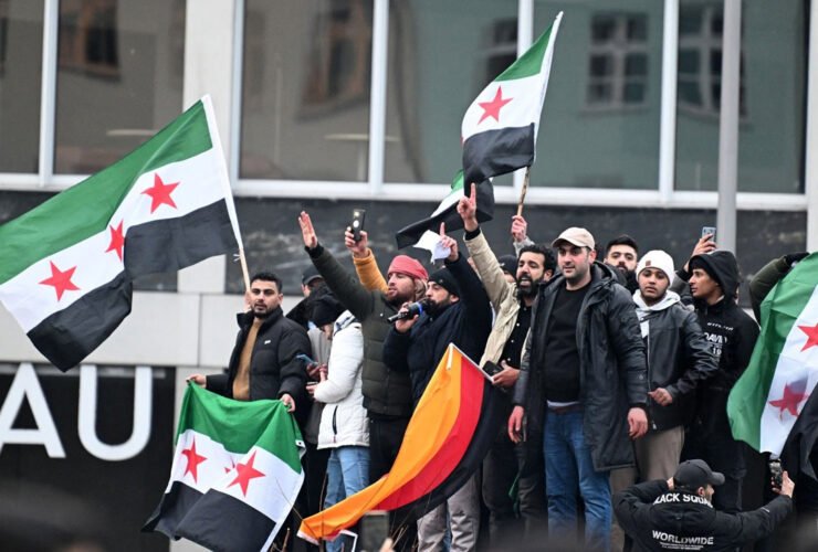 Menschen schwenken syrische Flaggen